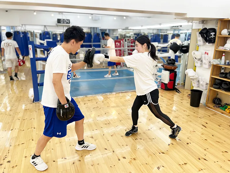 初心者がトレーナーとミット打ちの練習をしている風景